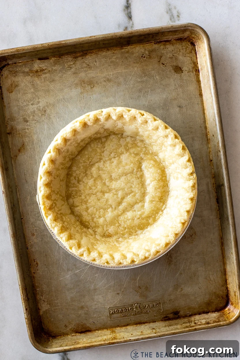 Overhead photo of a partially baked pie crust on a baking sheet