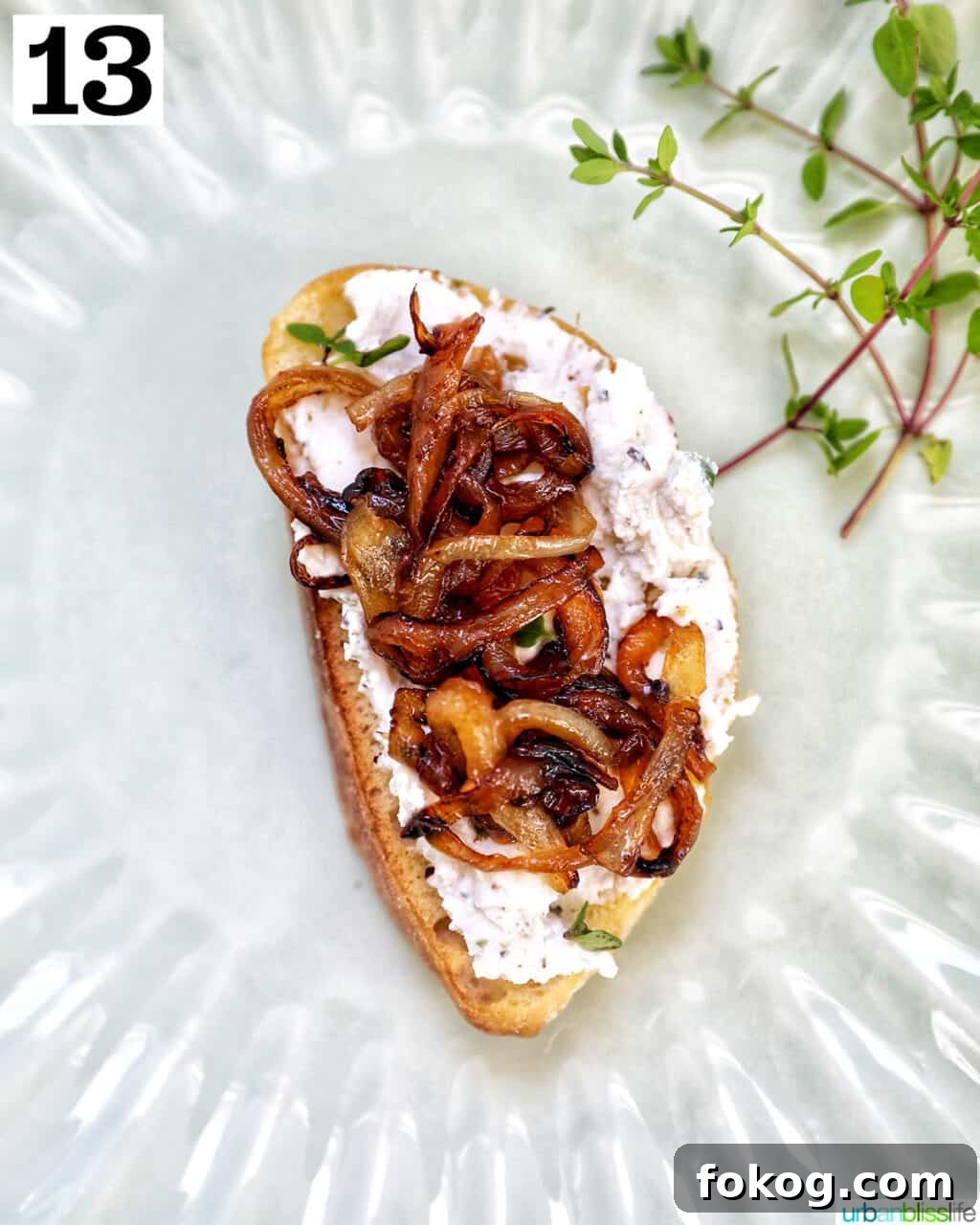caramelized onions on top of herbed goat cheese toast on a plate.