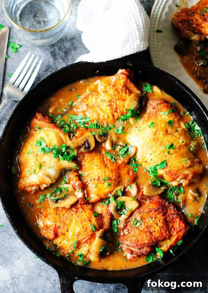 Chicken Chasseur or Hunter's Chicken Chicken Chasseur in a skillet with fork on a side and water behind