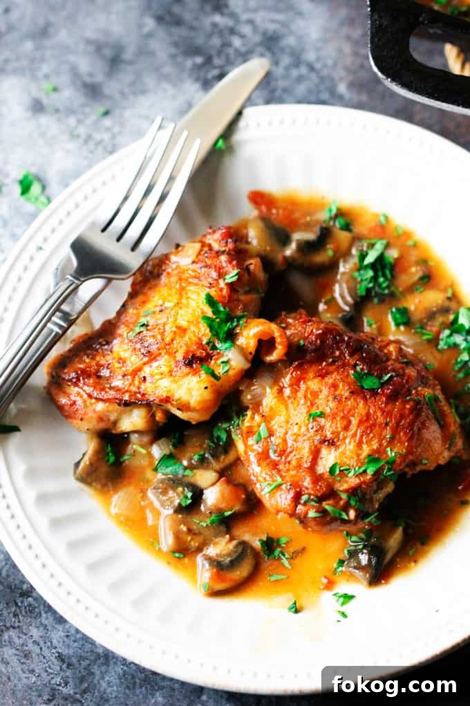 Chicken Chasseur or Hunter's Chicken French Hunters Chicken on w white plate with fork and knife