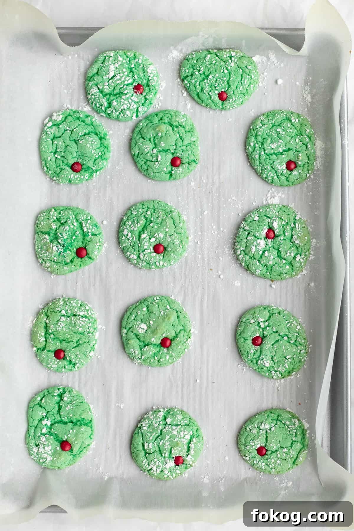 baked grinch cookies with m&m hearts on a cookie sheet
