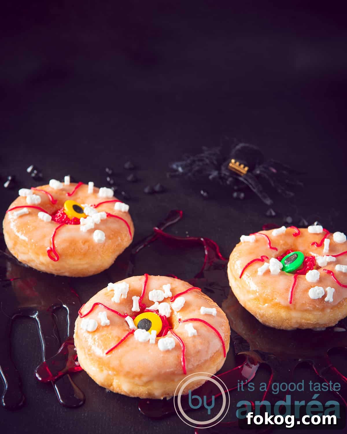 A trio of Halloween donuts with a terrible continuous eye on a dark background.