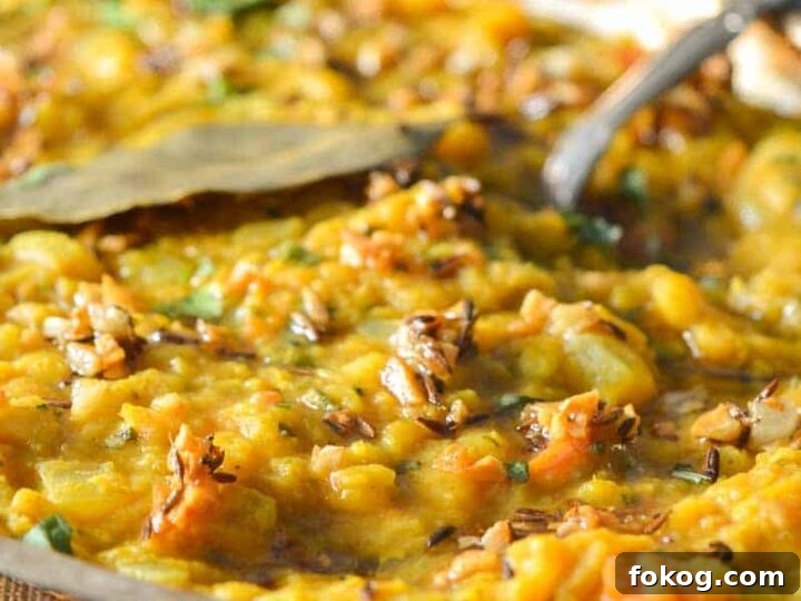 A silver bowl with dal tadka in it