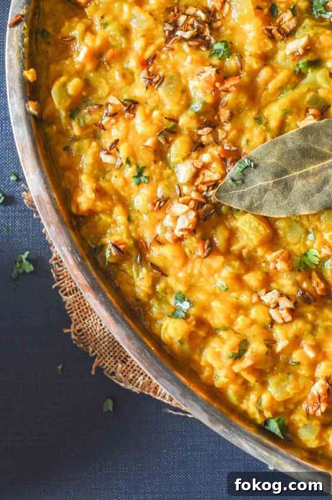 Restaurant-Style Dal Tadka Recipe Ready in 25 Minutes 3 A close up of yellow lentil curry with cumin and a bay leaf on top