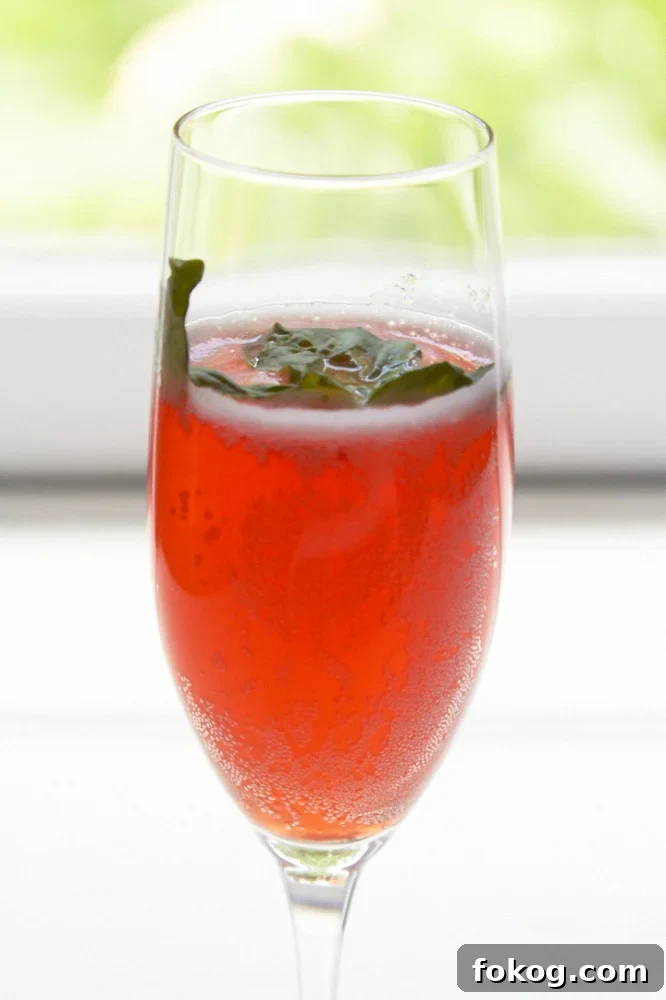 A champagne glass filled with strawberry-basil prosecco cocktail.