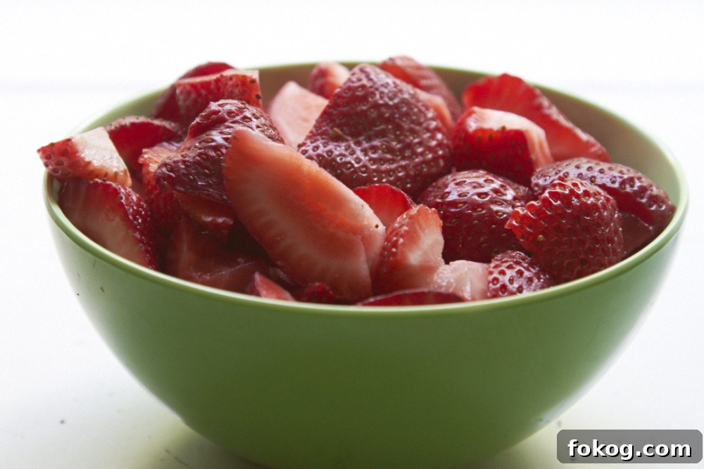 Sliced strawberries in a green bowl.