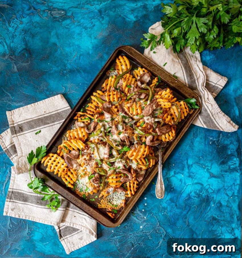 loaded cheesesteak fries on a platter. recipe from girlcarnivore.com