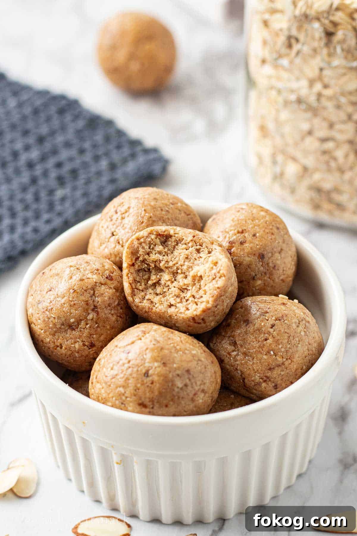 Almond Butter Protein Ball with bite mark in white bowl.