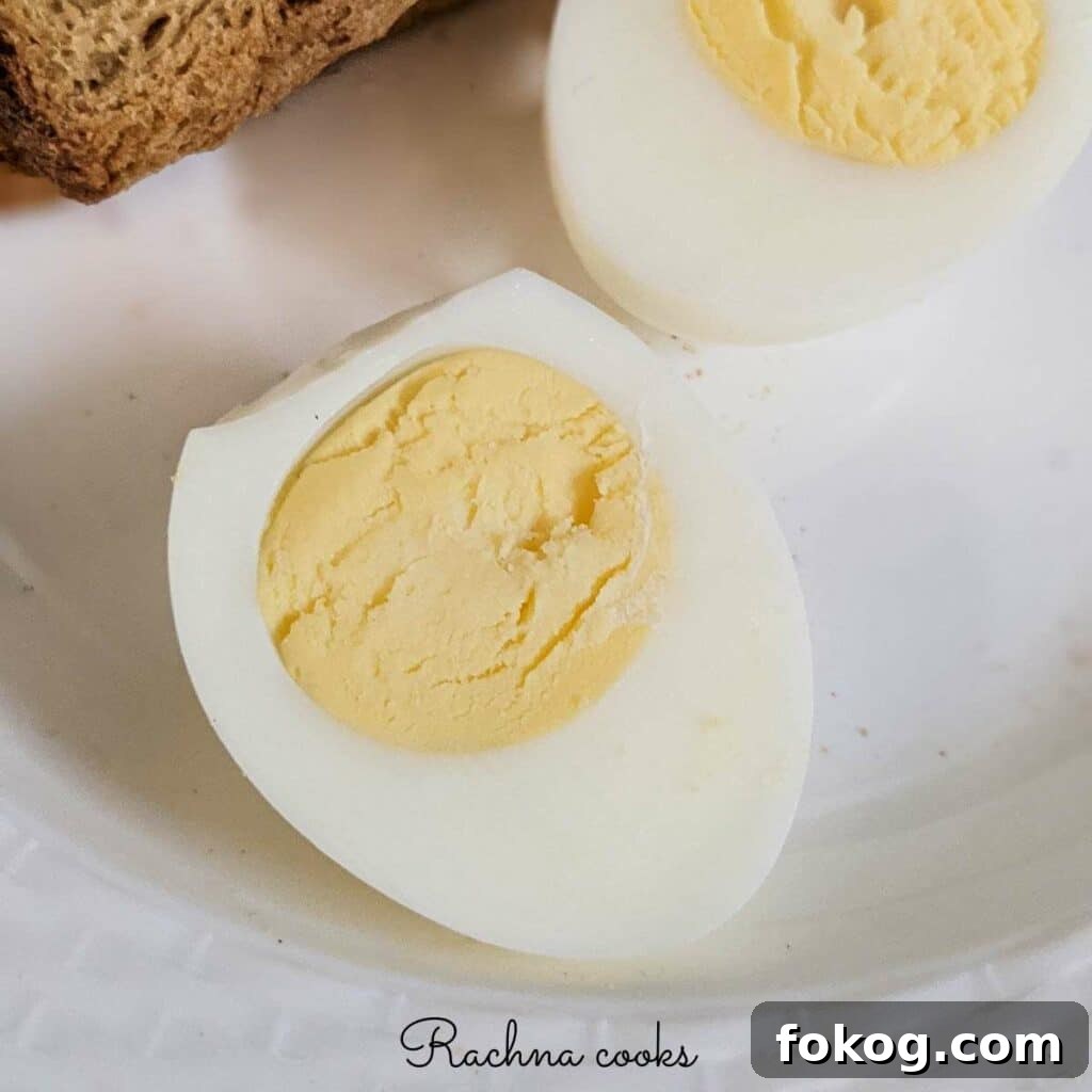 air fryer hard boiled egg cut into two after peeling on a white plate.