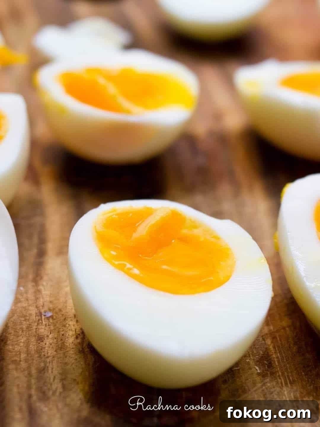 Air fryer jammy egg halves on a brown chopping board.