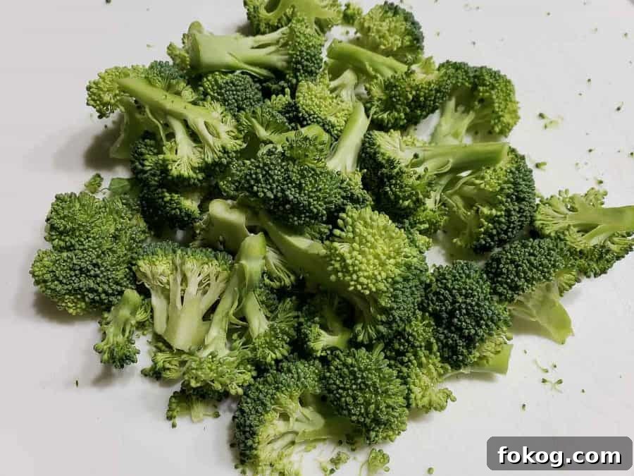 Creamy Chicken Fettuccine Alfredo Recipe for Weeknight Dinner 5 chopped broccoli on a cutting board.