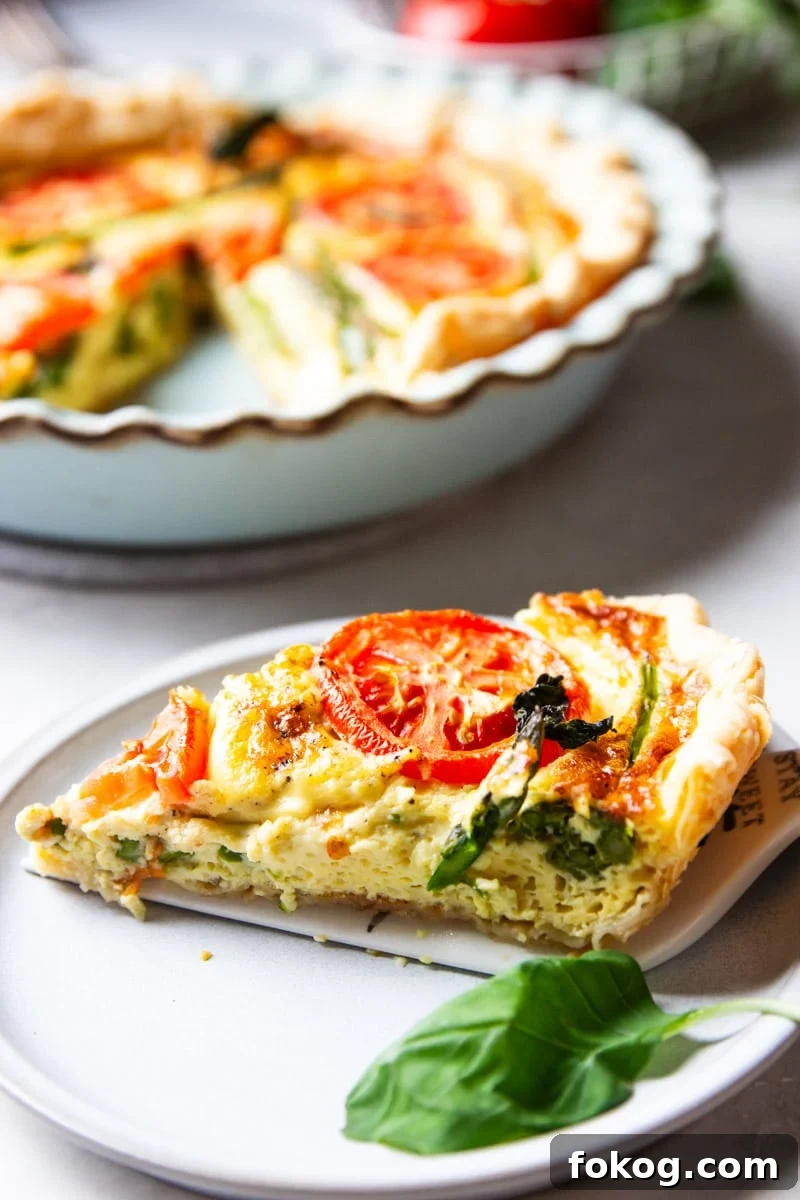Asparagus and tomato quiche, fresh basil, white plate. 