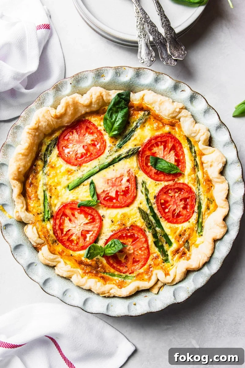 Tomato and asparagus quiche, forks, plates, fresh basil, white and red dish towel. 