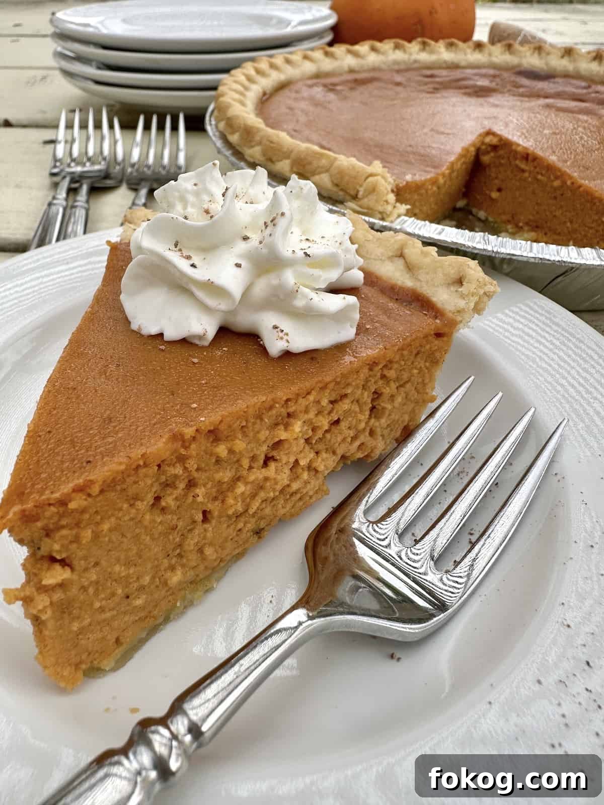 A slice of pumpkin pie with a fork on a plate.