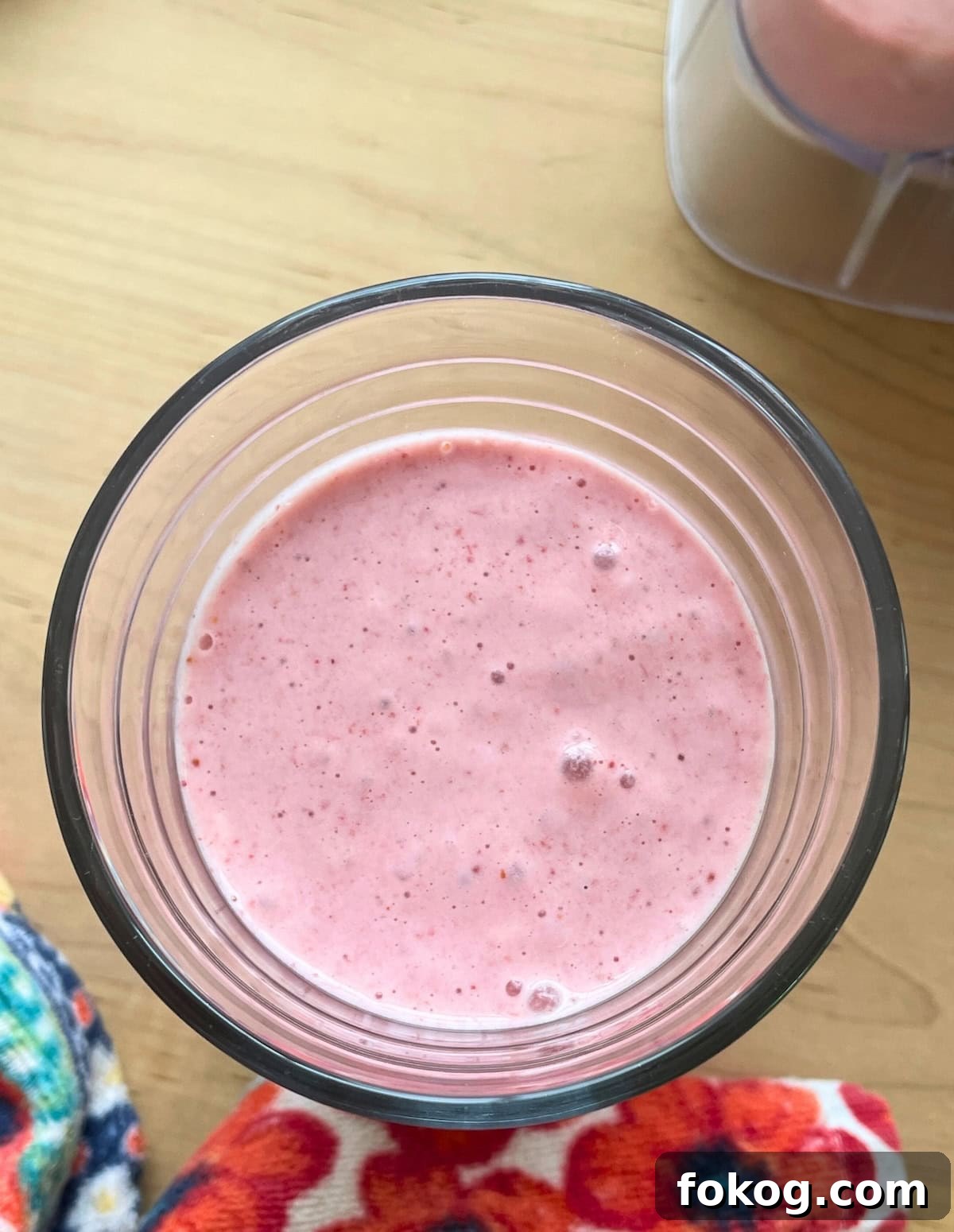 Strawberry Banana Yogurt Smoothie Recipe — Creamy & Refreshing 6 A close-up of a strawberry banana smoothie in a clear glass with a flowery towel.