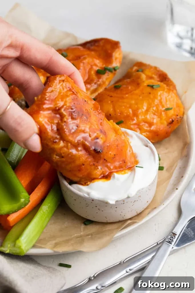 buffalo chicken thighs being dipped into sour cream