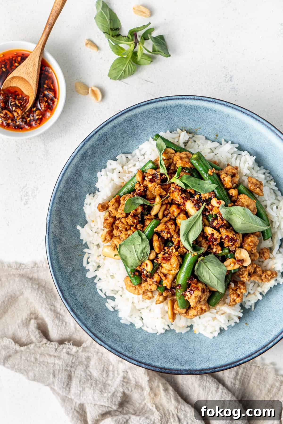 20-Minute Hoisin Chicken Stir-Fry Recipe for Weeknight Dinners 4 Close up of hoisin chicken stir fry in a blue bowl, over rice with Thai basil.
