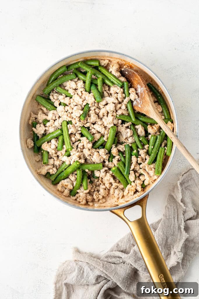 20-Minute Hoisin Chicken Stir-Fry Recipe for Weeknight Dinners 6 Adding green beans to chicken mince in a frying pan.
