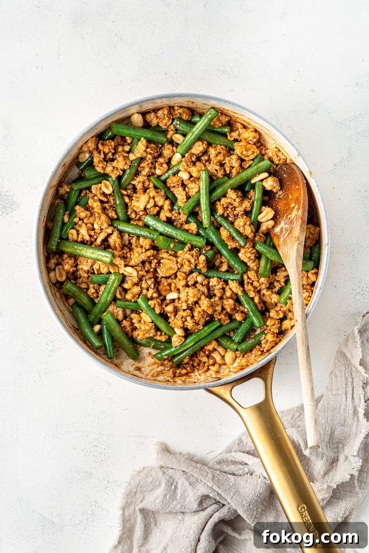 20-Minute Hoisin Chicken Stir-Fry Recipe for Weeknight Dinners 7 Hoisin chicken and beans with sauce in a frying pan with a wooden spoon.