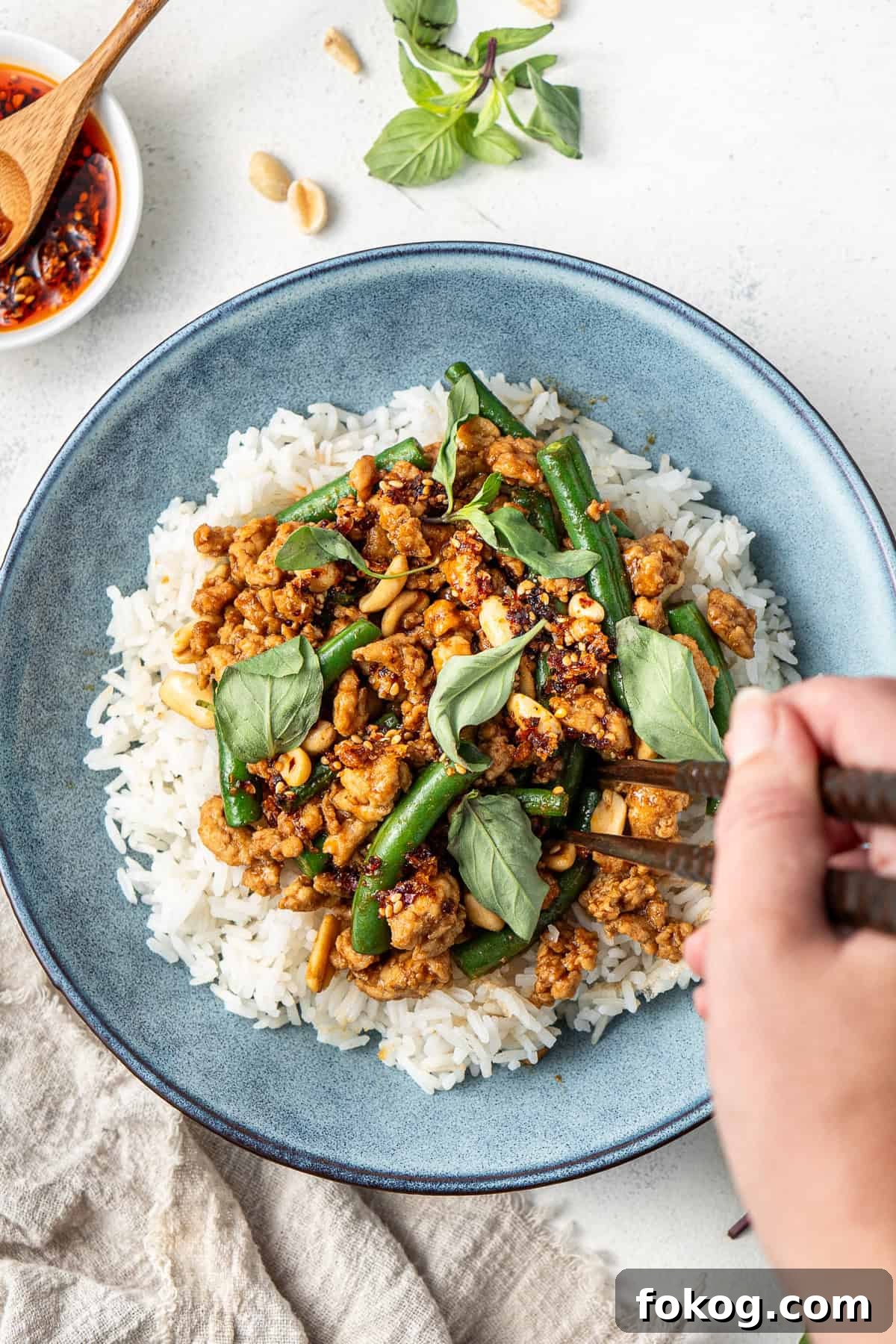20-Minute Hoisin Chicken Stir-Fry Recipe for Weeknight Dinners 8 A hand using chopsticks to take a bite of hoisin chicken stir fry and rice.
