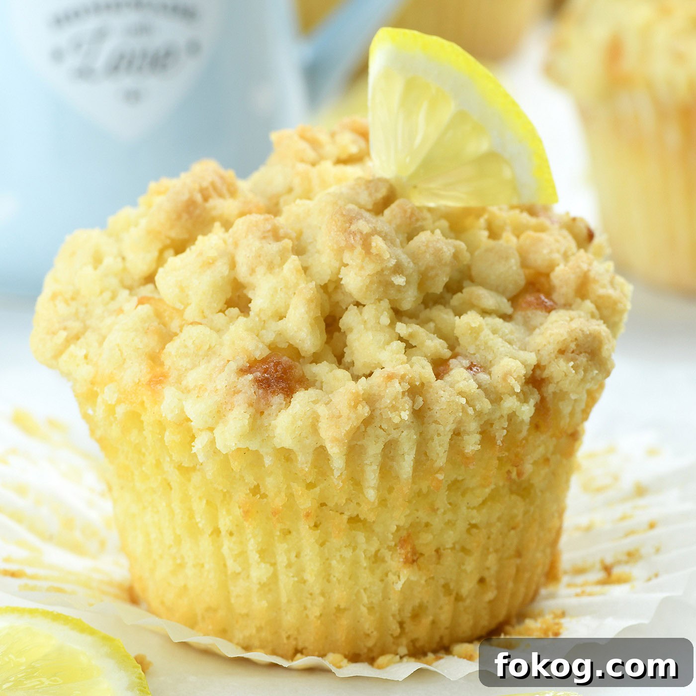 Lemon Curd Muffins with Zesty Citrus Filling 3 bakery style lemon muffin with crumb topping and fresh lemon slice on top