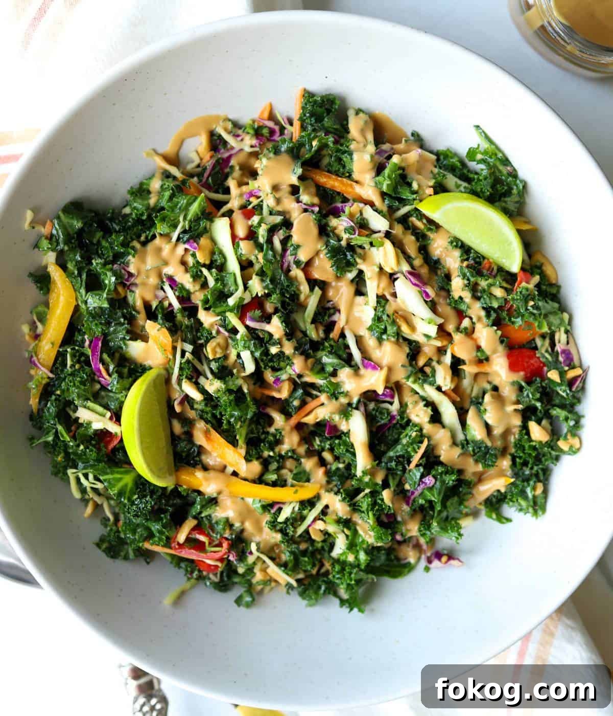 Crunchy kale salad with peanuts in bowl topped with lime.