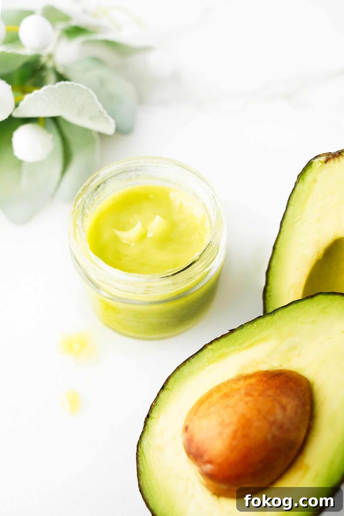 jelly jar with homemade avocado cream with a cut open avocado sitting next to it
