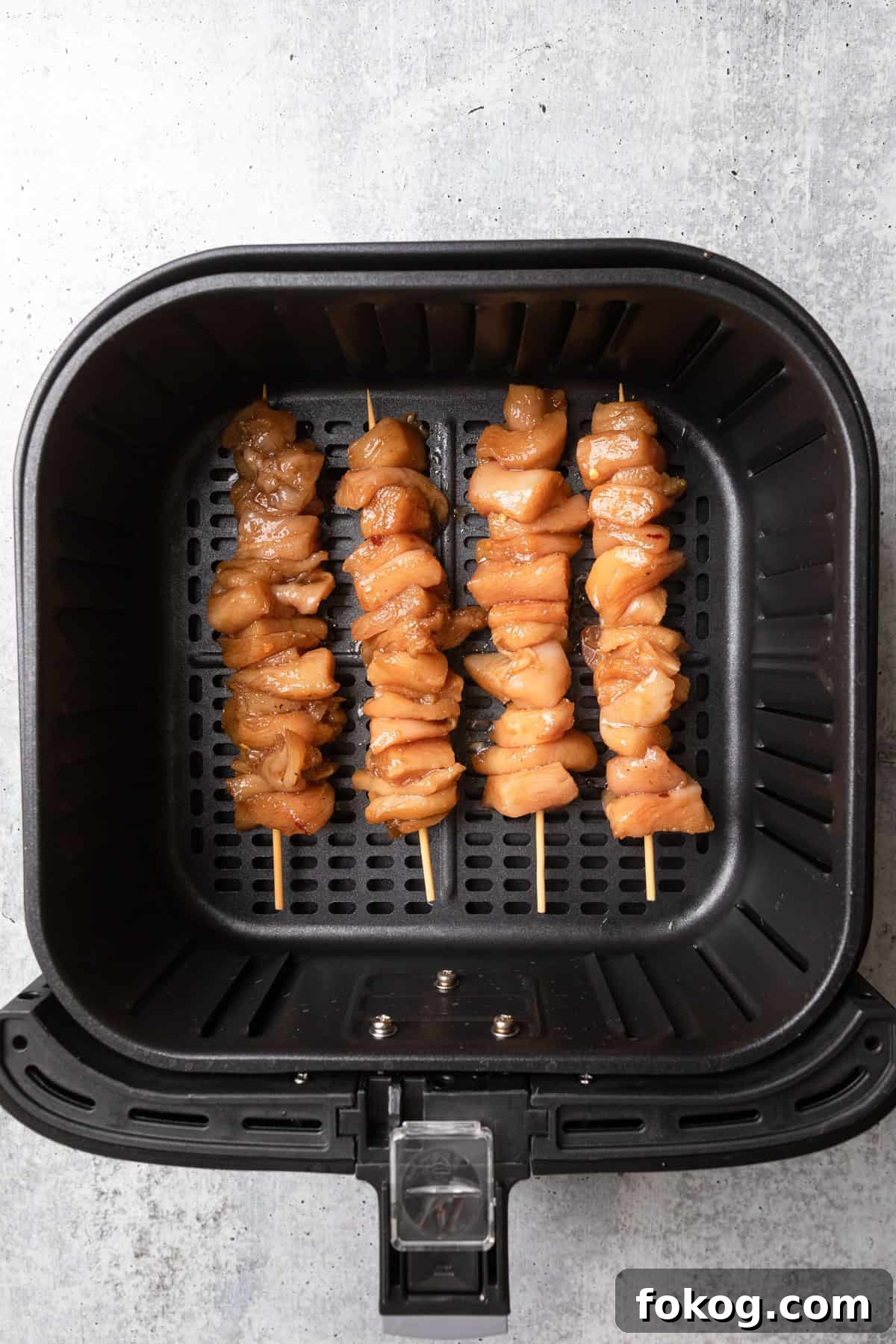 Air Fryer Chinese Chicken Skewers Recipe with Sticky Glaze 6 Raw skewered chicken placed in an air fryer basket.