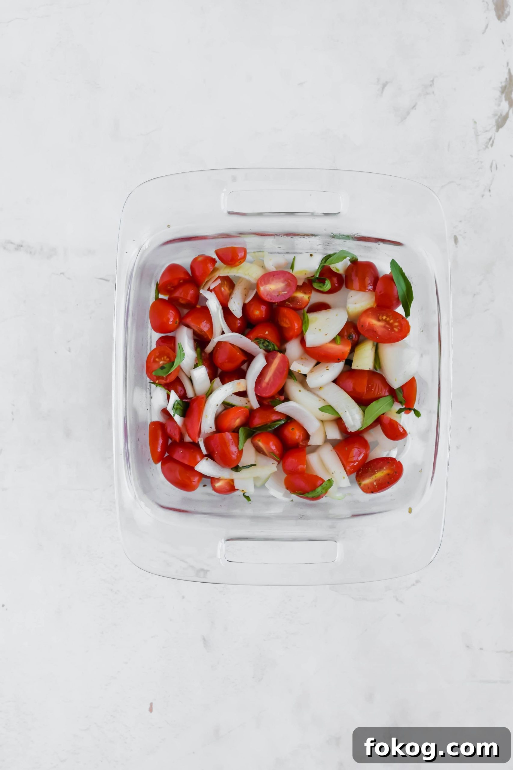onion and tomatoes in a glass baking dish for Cauliflower Gnocchi Soup.
