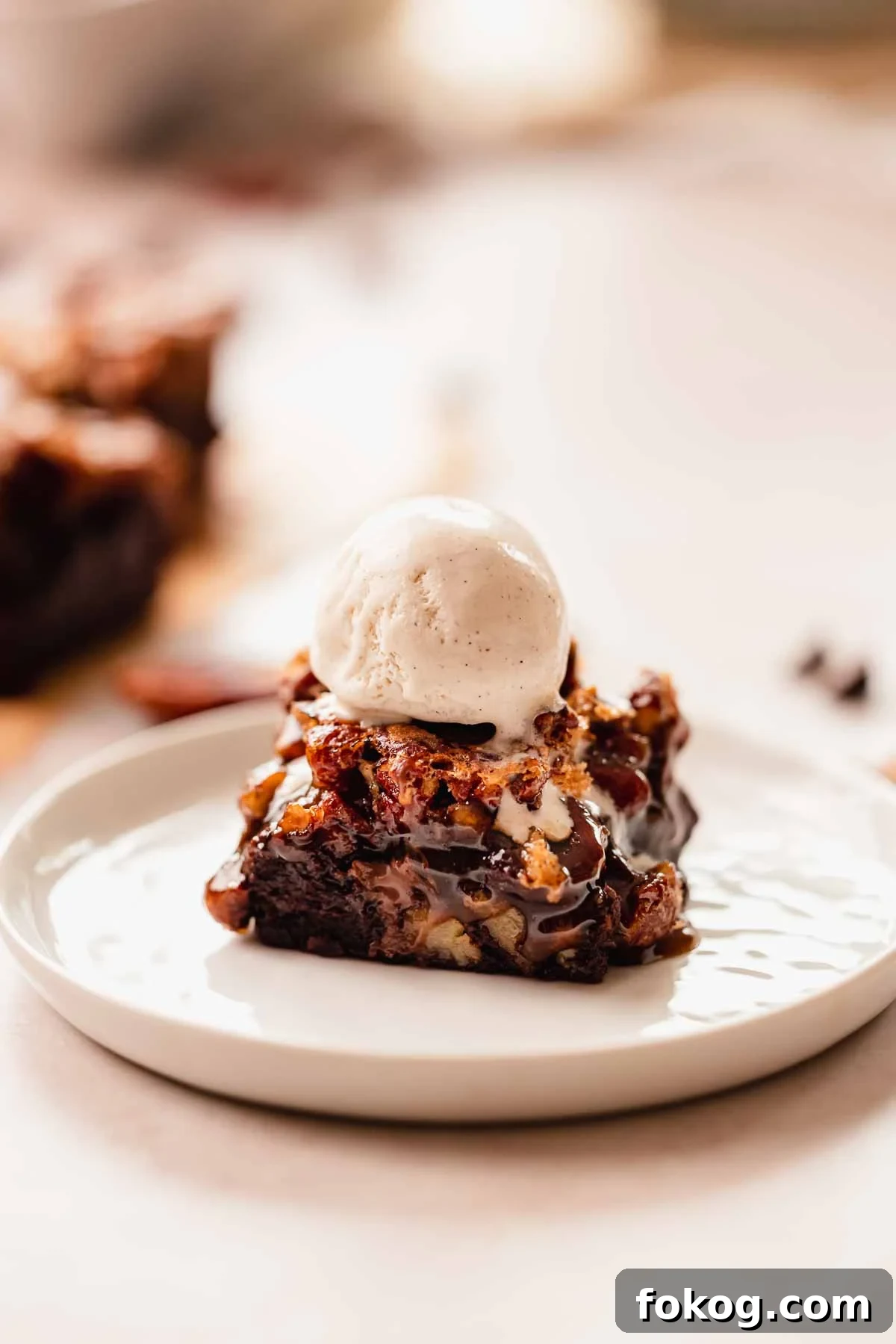 Decadent Pecan Pie Brownies Recipe — Gooey Pecan Swirl Dessert 3 a pecan brownie square with a scoop of vanilla bean ice cream on top sitting on a plate