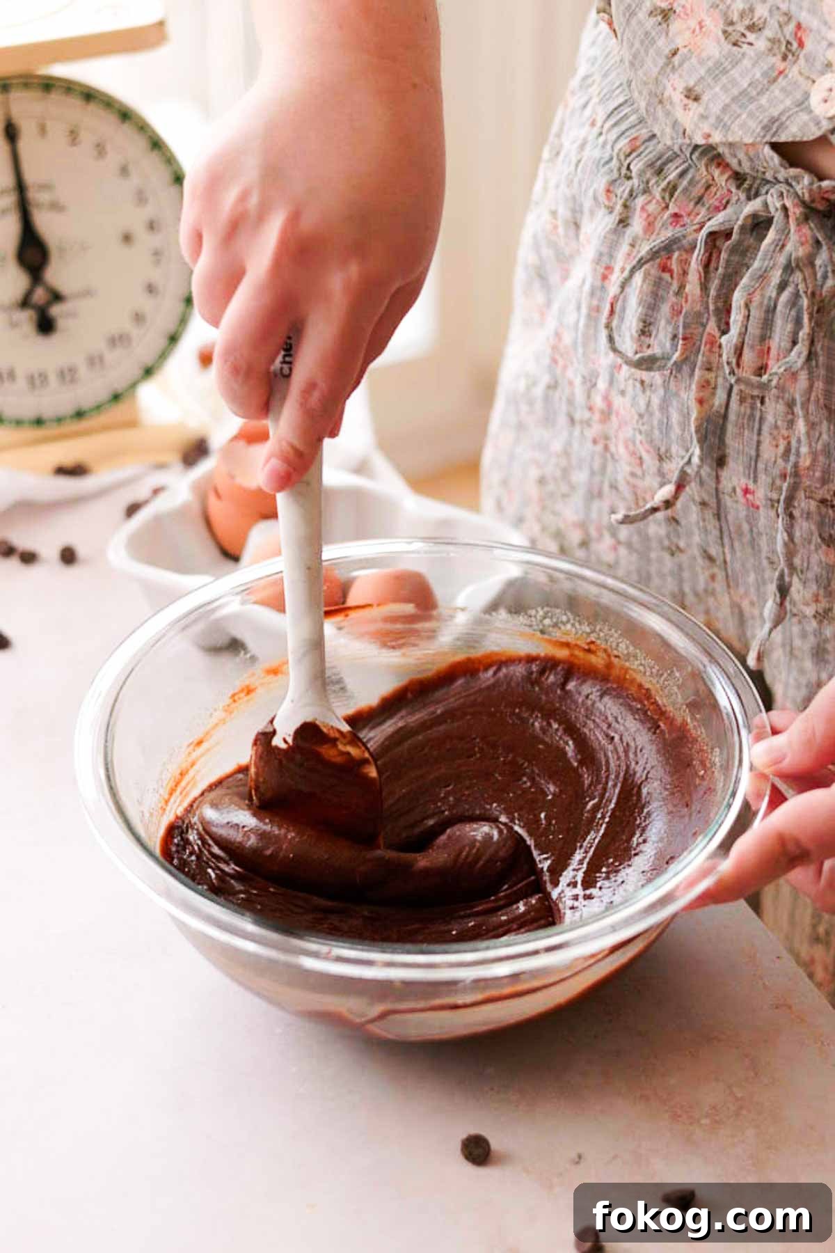 Decadent Pecan Pie Brownies Recipe — Gooey Pecan Swirl Dessert 7 stirring melted chocolate into brownie batter with a spatula in a glass bowl