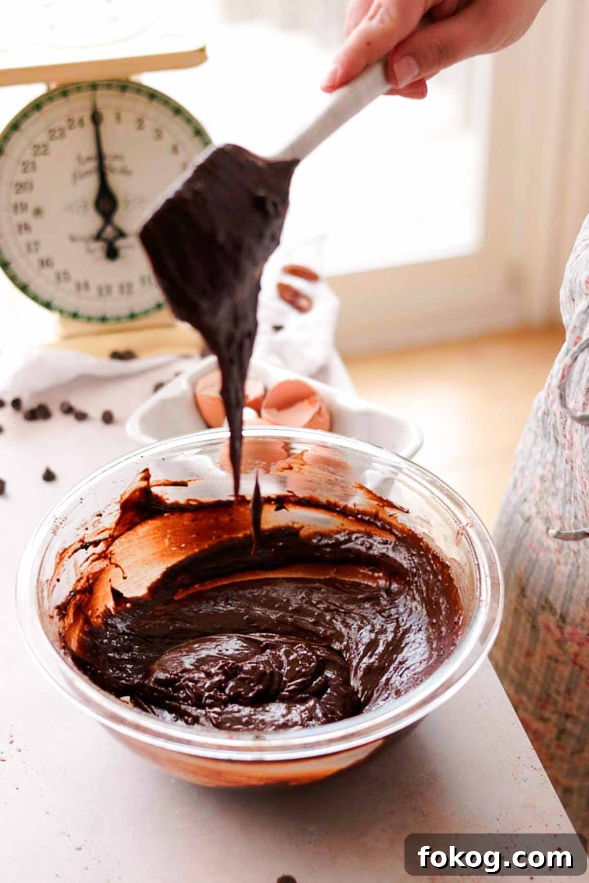 Decadent Pecan Pie Brownies Recipe — Gooey Pecan Swirl Dessert 8 raw brownie batter falling off of a silicone spatula into a bowl of batter