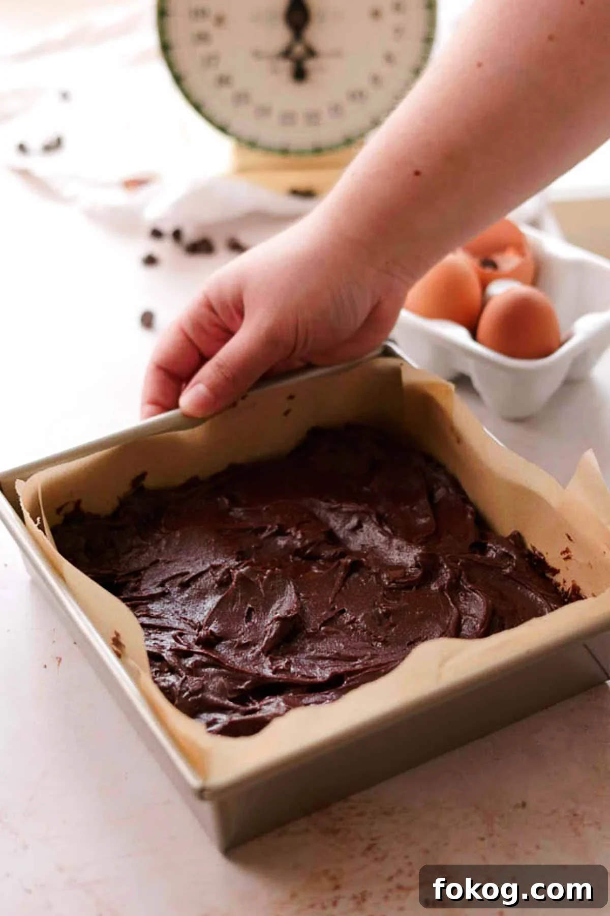Decadent Pecan Pie Brownies Recipe — Gooey Pecan Swirl Dessert 10 spread brownie batter in a square tin pan with parchment paper
