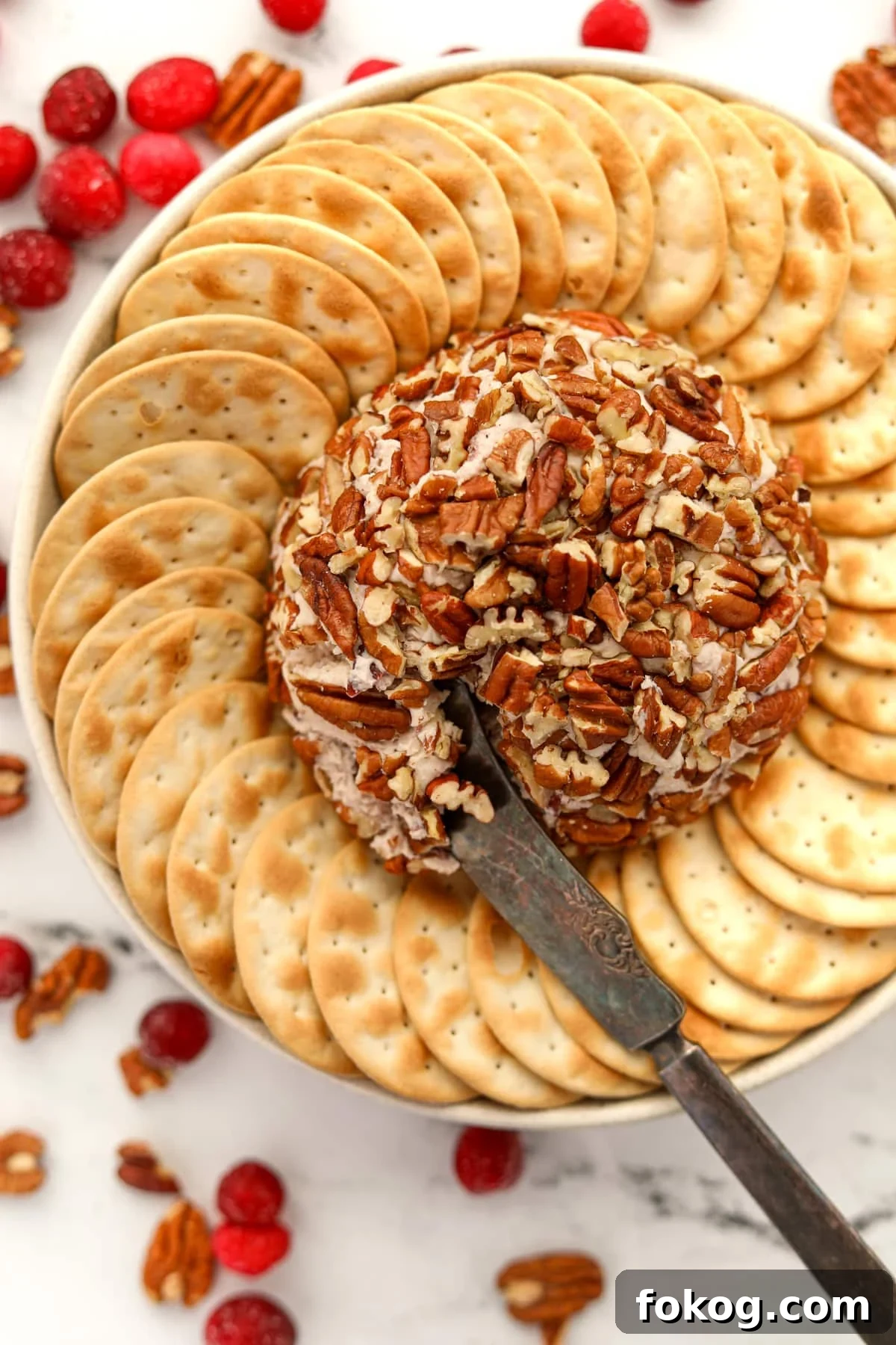 Creamy Boursin Cheese Ball Recipe for Parties and Holidays 2 An appetizer knife taking a portion of a cheese ball from a serving platter.