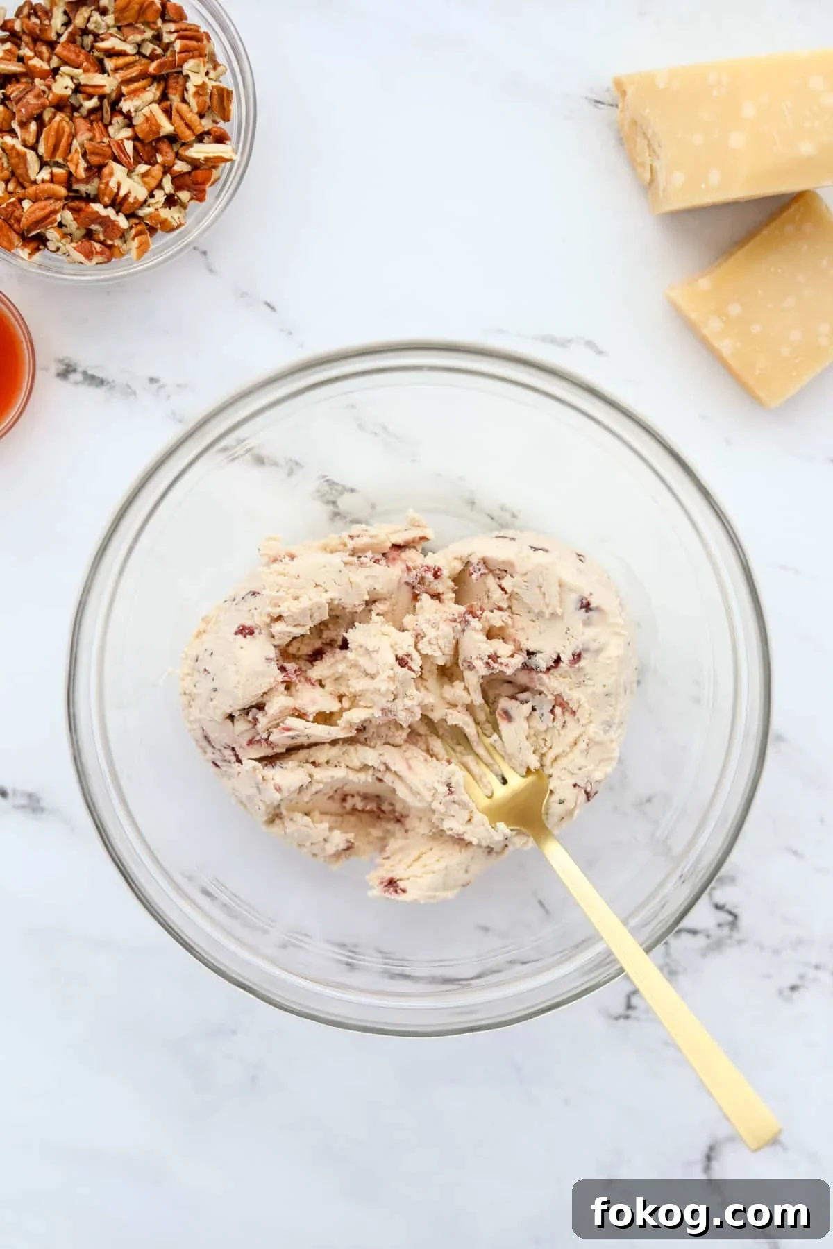 Creamy Boursin Cheese Ball Recipe for Parties and Holidays 4 A fork mashing soft cheese in a mixing bowl.