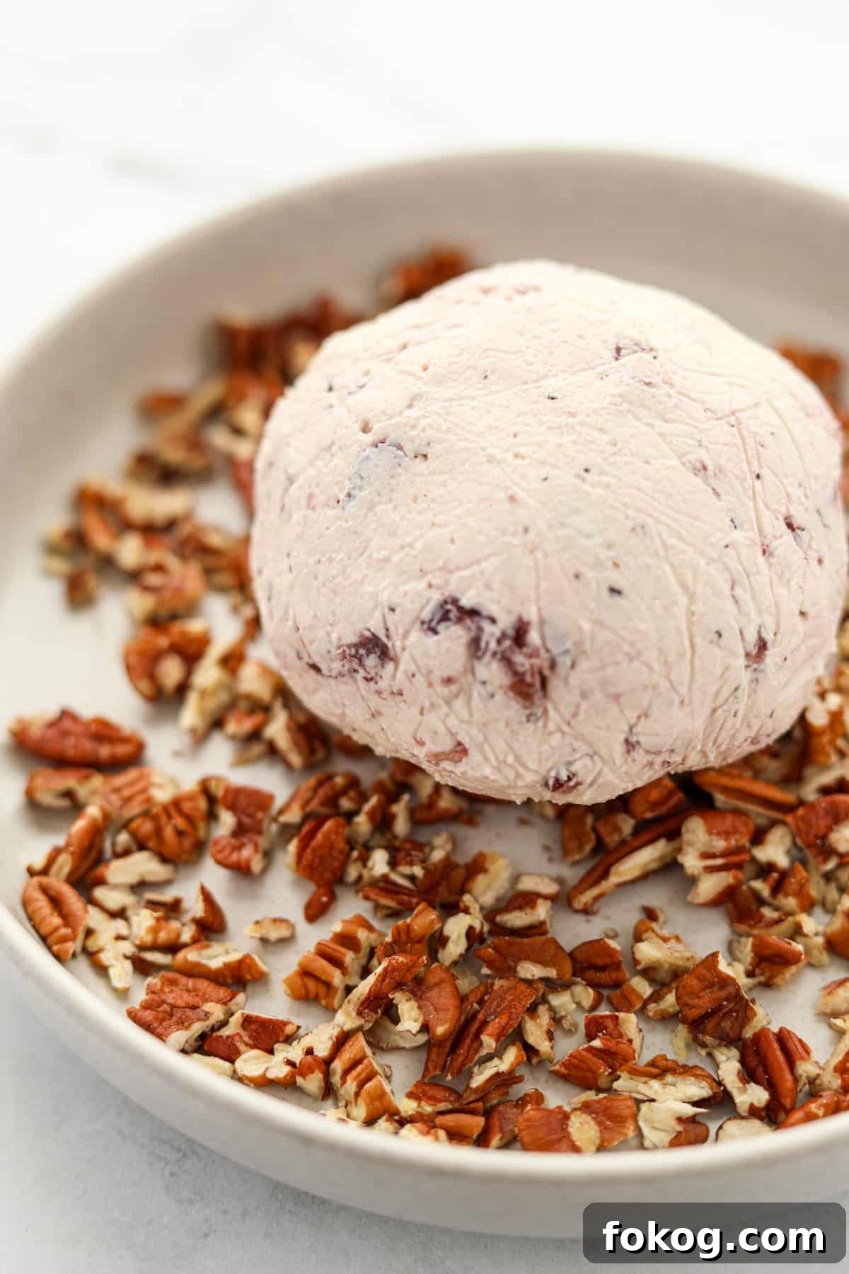 Creamy Boursin Cheese Ball Recipe for Parties and Holidays 6 Rolling a chilled ball of soft cheese in chopped pecans.