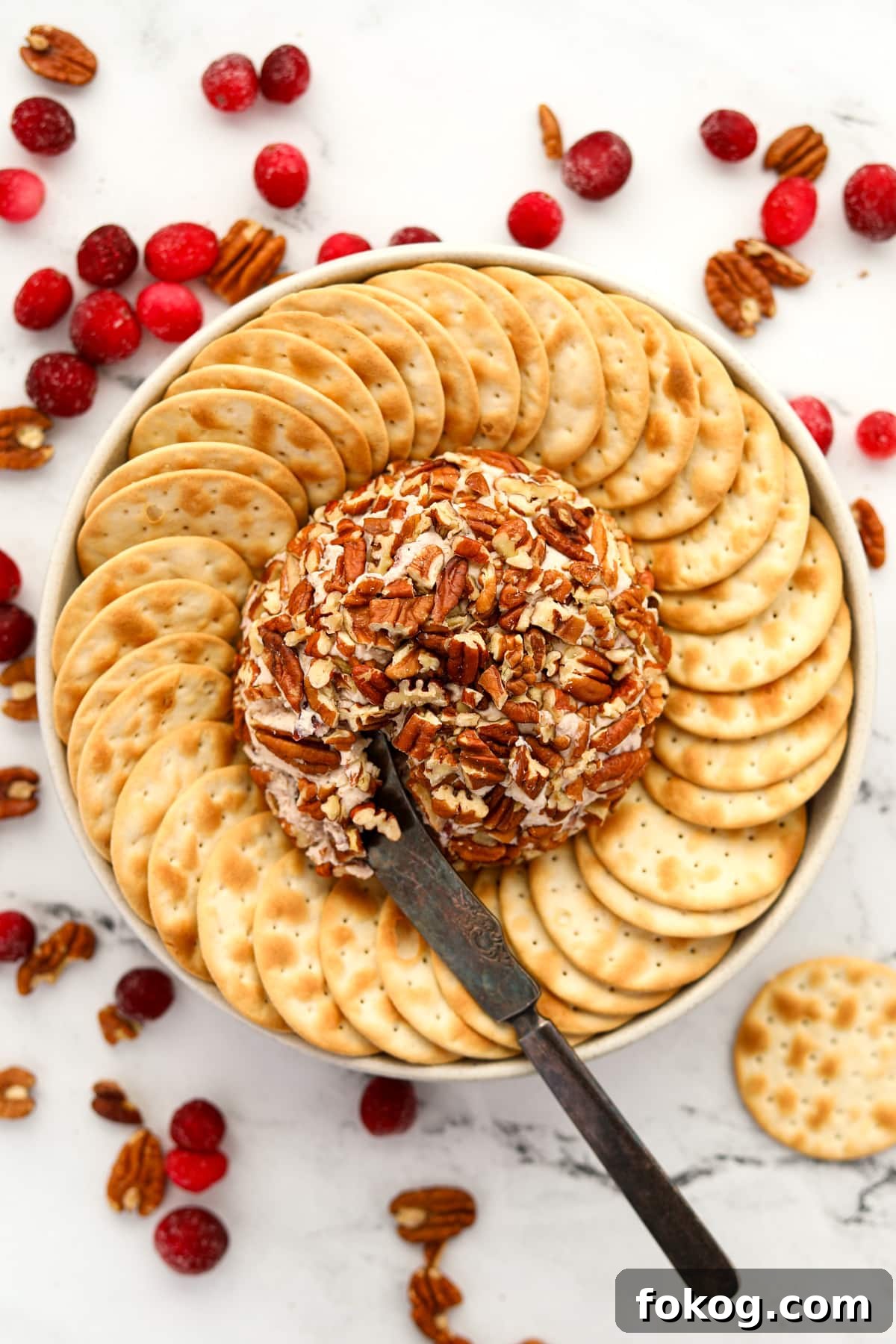Creamy Boursin Cheese Ball Recipe for Parties and Holidays 9 An appetizer knife taking a portion of a pecan-coated cheese ball.