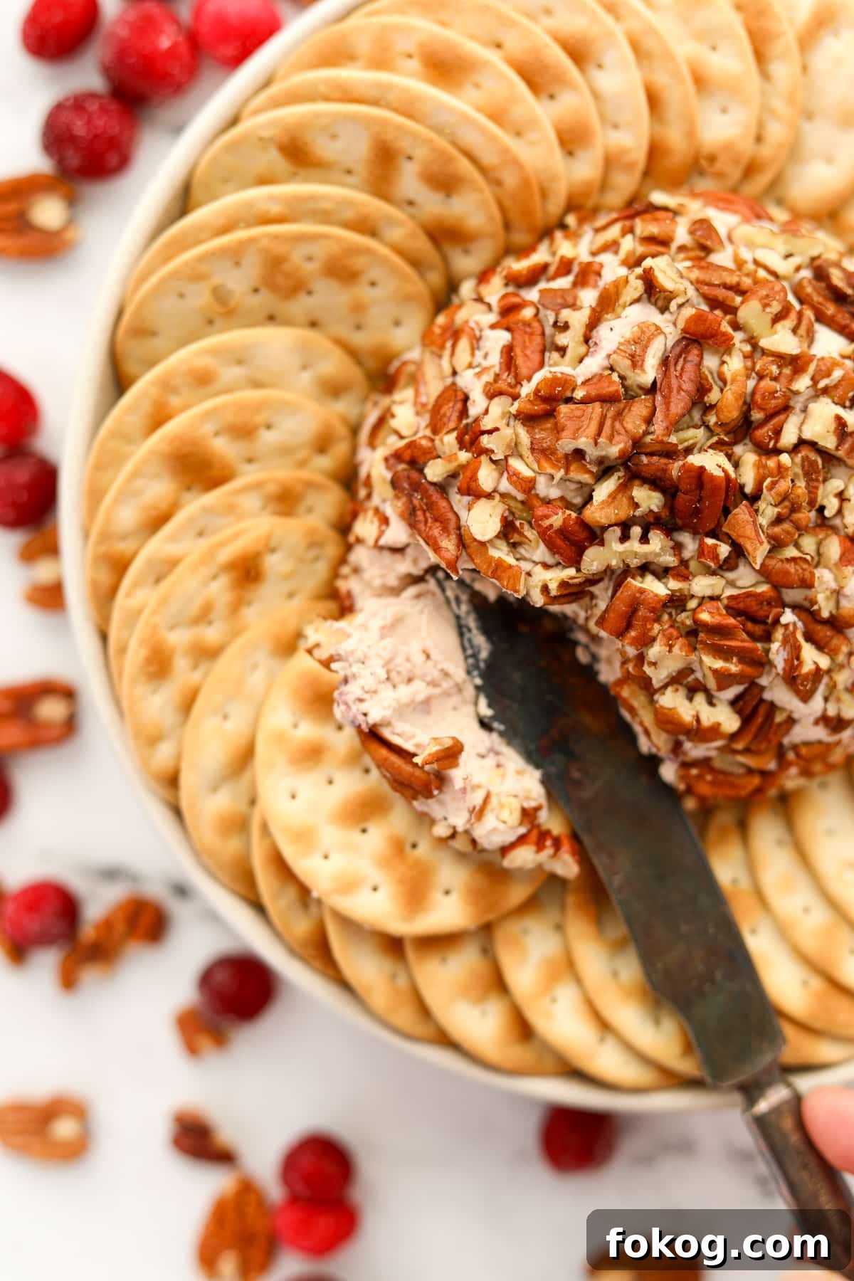 Creamy Boursin Cheese Ball Recipe for Parties and Holidays 10 An appetizer knife spreading soft cheese from a nut-wrapped cheese ball.