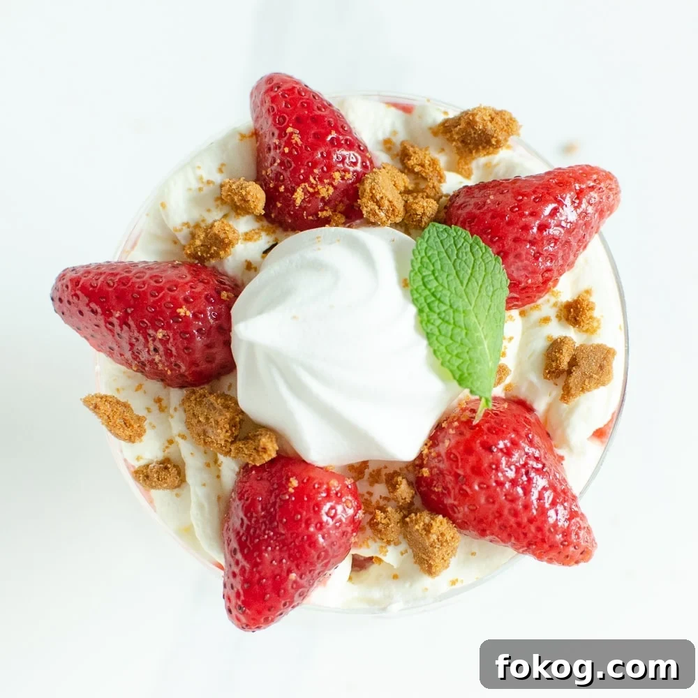 Crushed biscuit and mint leaf placed on top of the cream and strawberries in a glass to create our Eton mess dessert