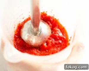 Blending strawberries in a jug using a hand held blender