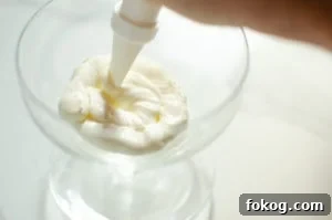 whipped cream being piped into a cold glass to make Eton mess dessert