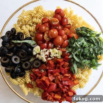 Classic Italian Pasta Salad Recipe with Tangy Vinaigrette and Veggies 6 pasta with cherry tomatoes, olives, basil, roasted red peppers, and garlic on top but not mixed in.