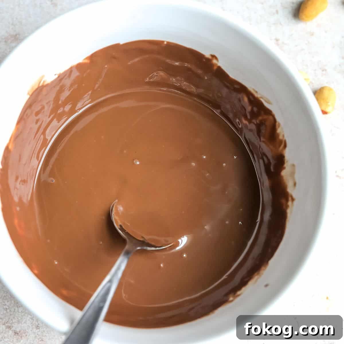 Buckeye Bars Recipe: Classic Peanut Butter Chocolate Treats 5 White bowl with melted chocolate and a spoon.
