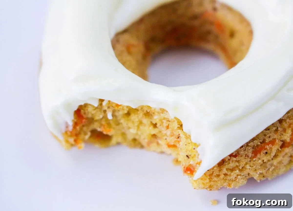 Close up of a carrot cake donut with a bite missing.