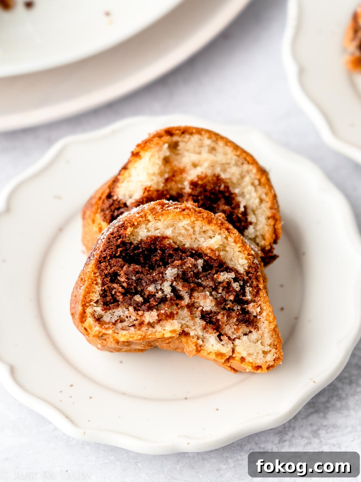 Moist Eggless Marble Cake Recipe for Perfect Swirls 4 Two slices of eggless marble cake on a white plate.