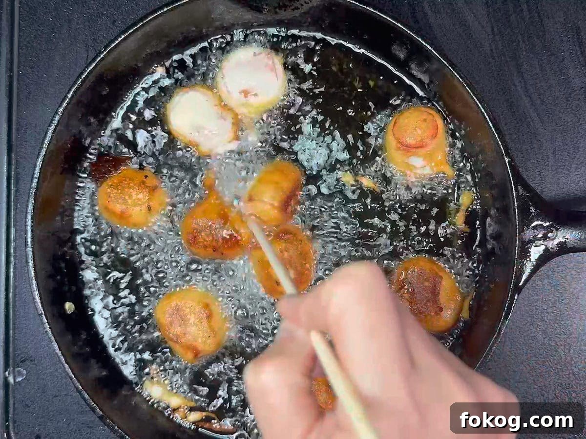 Mini Corn Dog Bites Recipe: Crispy, Bite-Sized Snack Ideas 21 Using a wooden skewer to flip the mini corn dog pieces over in the hot oil.