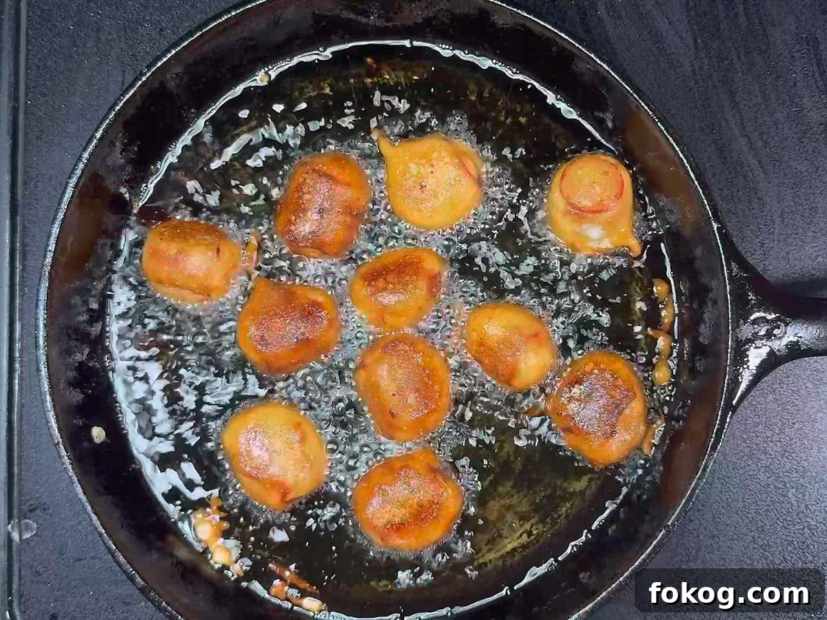 Mini Corn Dog Bites Recipe: Crispy, Bite-Sized Snack Ideas 22 Browned mini corn dog bites frying in the hot oil.