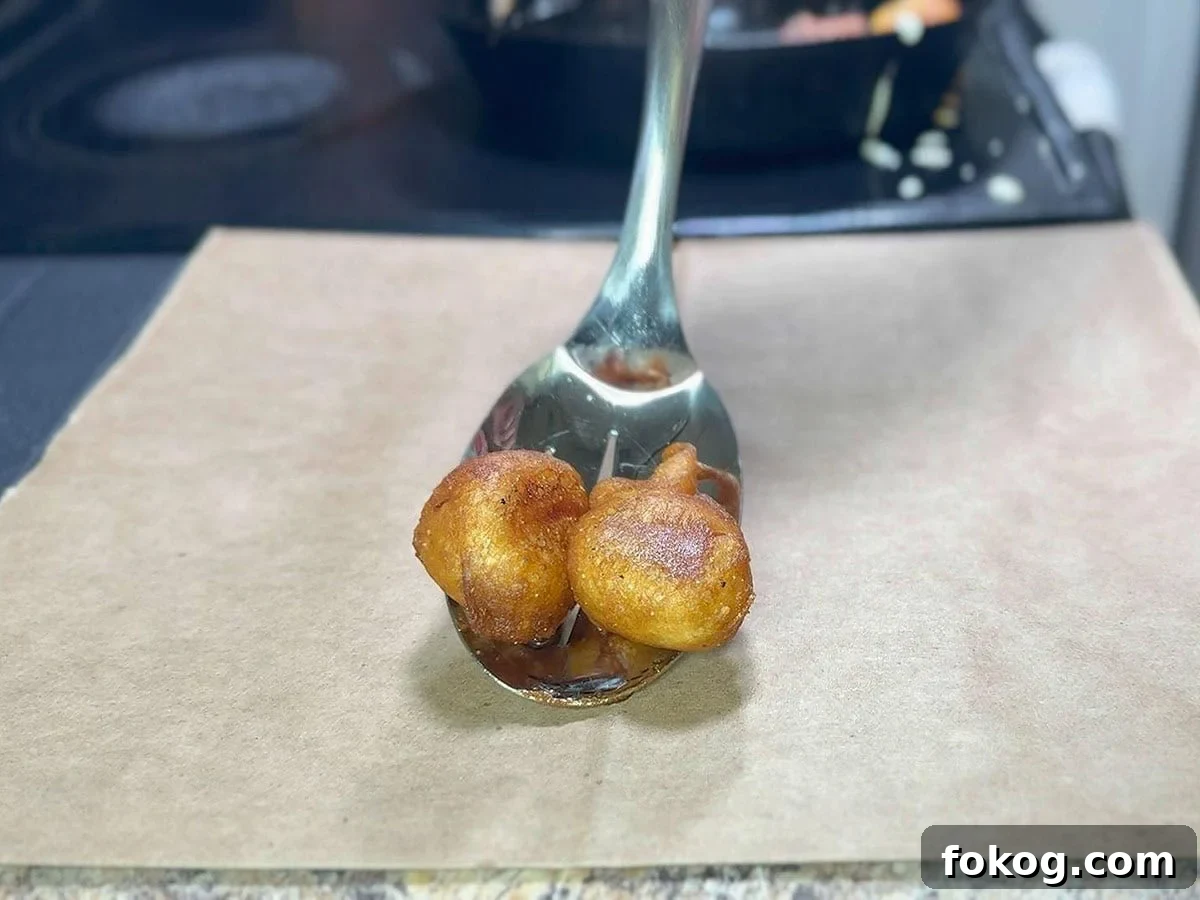Mini Corn Dog Bites Recipe: Crispy, Bite-Sized Snack Ideas 23 Removing the mini corn dog bites with a slotted spoon onto a brown paper sack.