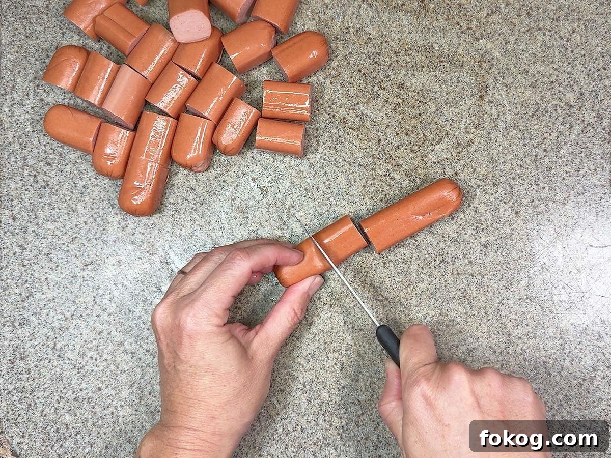 Mini Corn Dog Bites Recipe: Crispy, Bite-Sized Snack Ideas 5 Hands using a paring knife to cut hot dogs into smaller pieces.