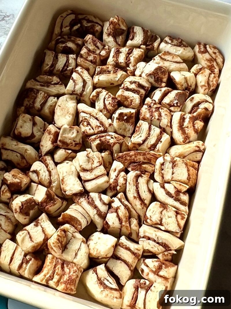 Cinnamon Roll French Toast Casserole Recipe for Brunch Bliss 4 Cinnamon rolls pieces in a single layer in baking dish with melted butter.